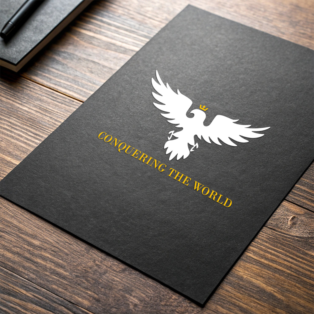 Bold white eagle emblem with crown and sword on black textured card mockup, featuring gold "CONQUERING THE WORLD" text, presented on wooden surface with notebook and pen